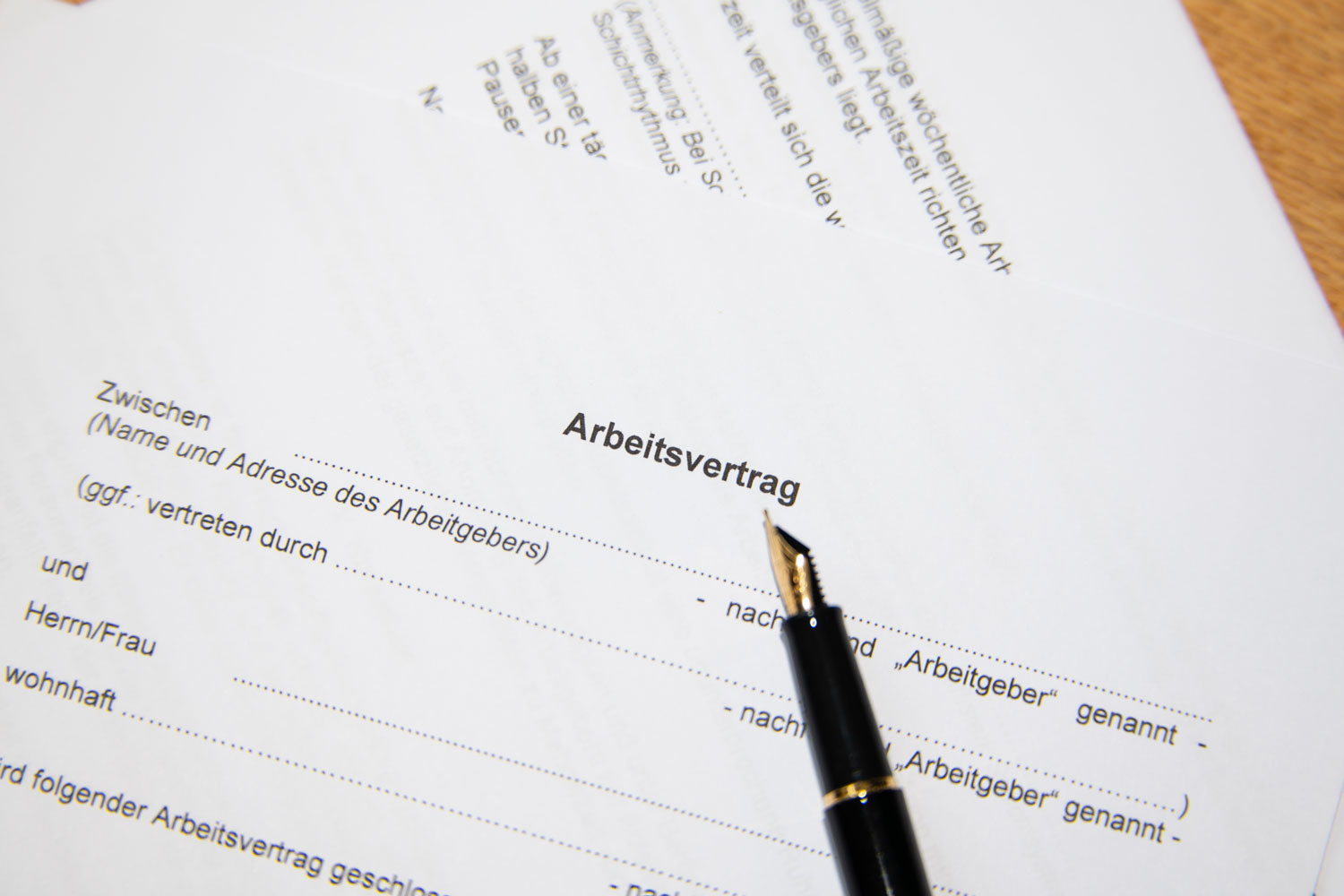 Ein ausgedruckter deutscher Arbeitsvertrag liegt bereit zum Unterschreiben, darauf liegt ein edler schwarzer Füller.