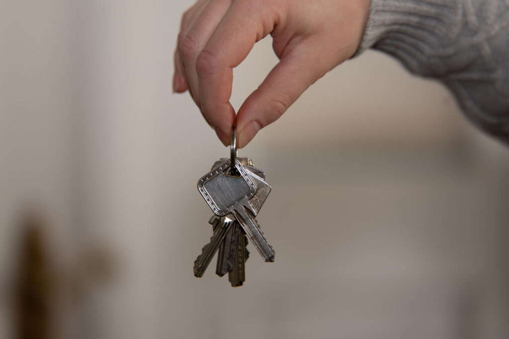 Eine Hand hält einen dicken Schlüsselbund mit mehreren Schlüsseln für ein neues Haus oder eine Mietwohnung.
