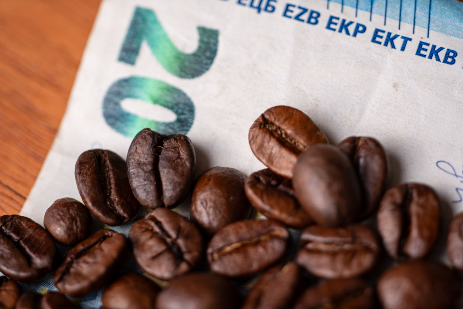Dunkel geröstete Kaffeebohnen liegen auf einem 20-Euro-Geldschein.